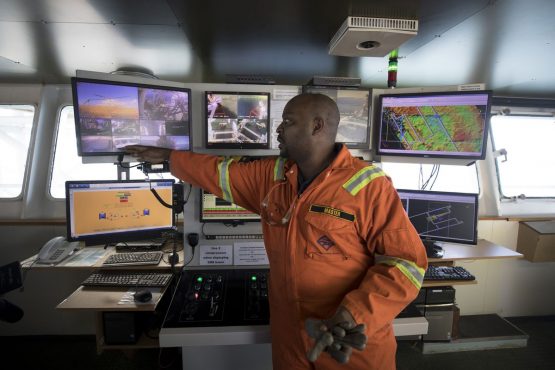 A crew member points to a digital monitors showing camera views of mooring systems in the operations room aboard the Mafuta. The vessel positions itself to scan and sample the seabed to identify the most profitable area for the ship to suck up the gems. Picture: Simon Dawson/Bloomberg