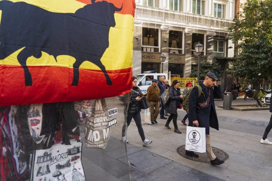 Pedestrians pass a tourist souvenir stall on a street in central Madrid, Spain. Image: Angel Navarrete/Bloomberg